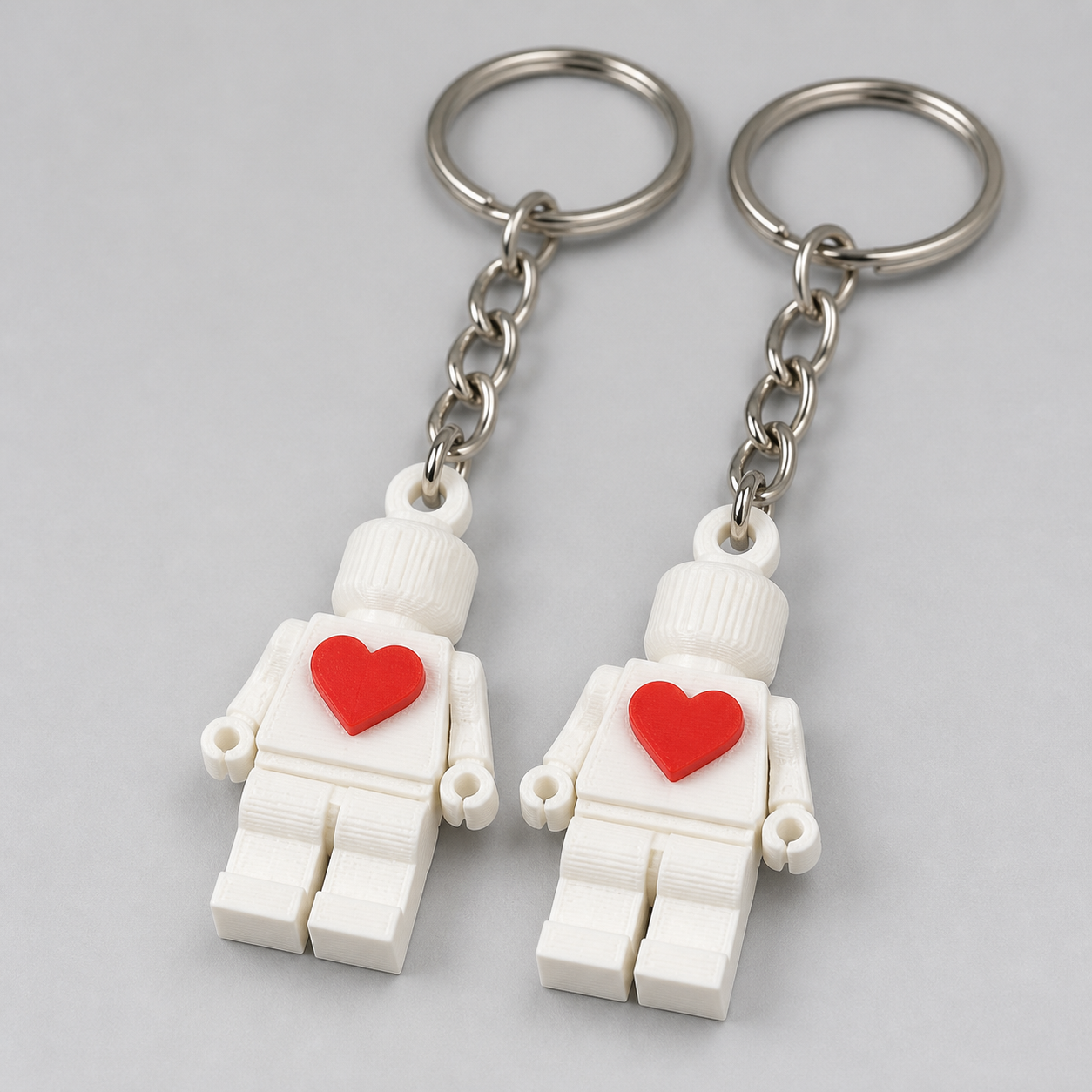 Close view of two white keychain figures with red hearts